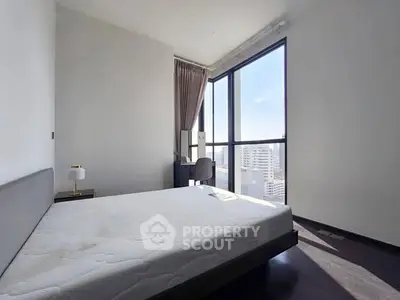 Spacious bedroom with large windows offering stunning city views and ample natural light.