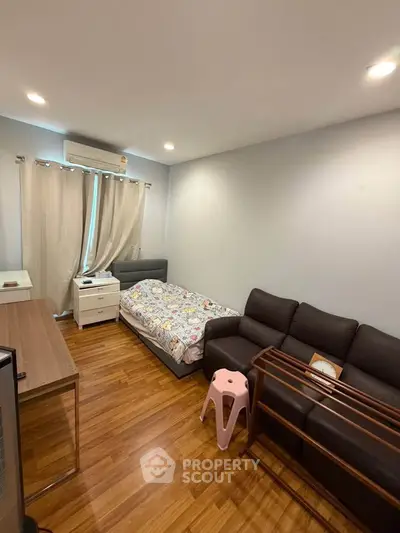 Cozy bedroom with wooden flooring, modern furniture, and ample natural light.