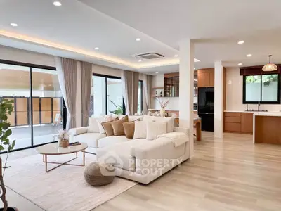 Spacious modern living room with open kitchen and large windows, perfect for family gatherings.
