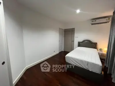 Spacious bedroom with wooden flooring and modern furnishings in a cozy apartment.