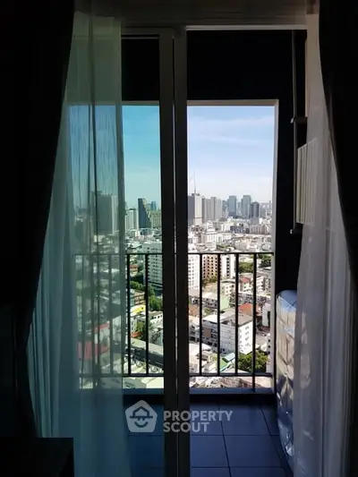 Stunning city view from a modern apartment balcony with glass doors and curtains.
