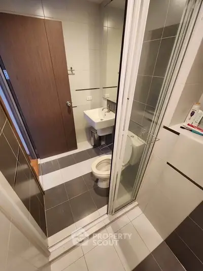 Compact modern bathroom with shower and sleek fixtures in urban apartment.