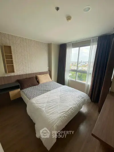 Cozy bedroom with large window offering a scenic city view, featuring modern decor and ample natural light.
