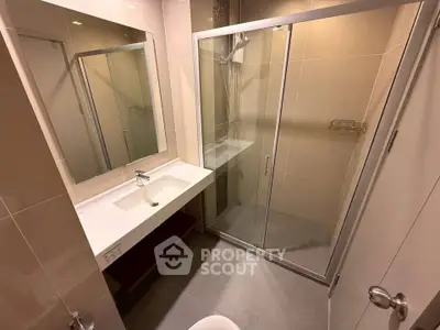 Modern bathroom with glass shower enclosure and sleek vanity in a contemporary apartment.