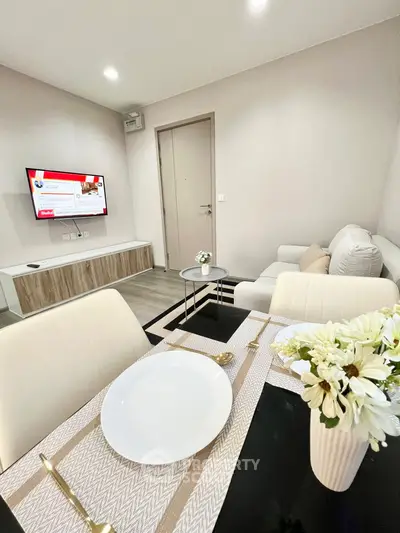 Modern living room with elegant dining setup and wall-mounted TV