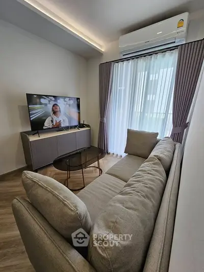 Modern living room with sleek furniture and large window, featuring a cozy sofa and flat-screen TV.
