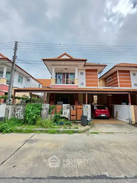 Charming two-story house with carport and lush greenery in a suburban neighborhood.