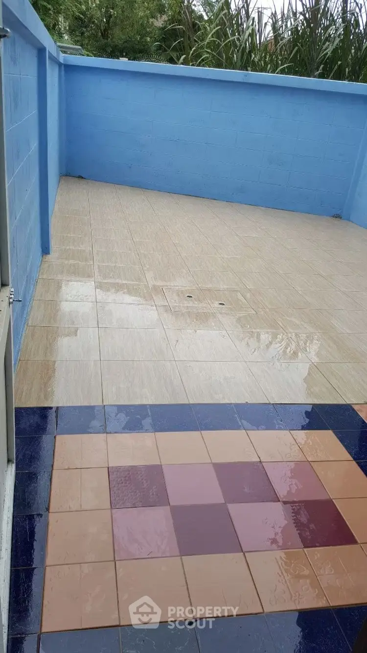 Spacious tiled balcony with blue walls and open sky view, perfect for outdoor relaxation.