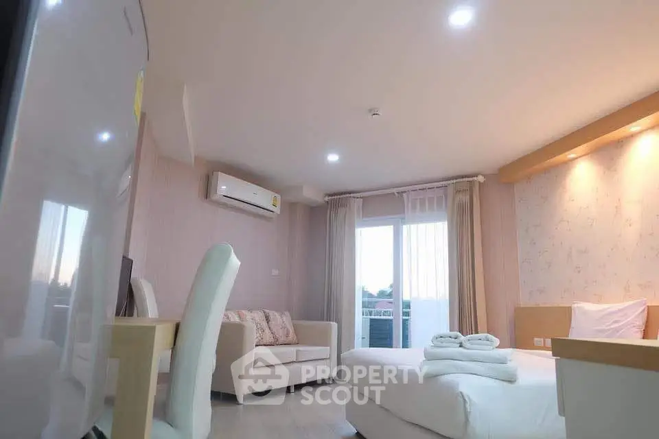 Modern bedroom with cozy seating area and balcony access in a stylish apartment.