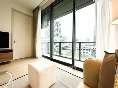 Modern living room with large windows and city view, featuring cozy seating and elegant decor.