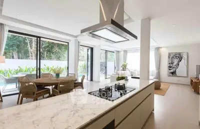 Luxurious open-plan kitchen and living room with pool view and modern decor