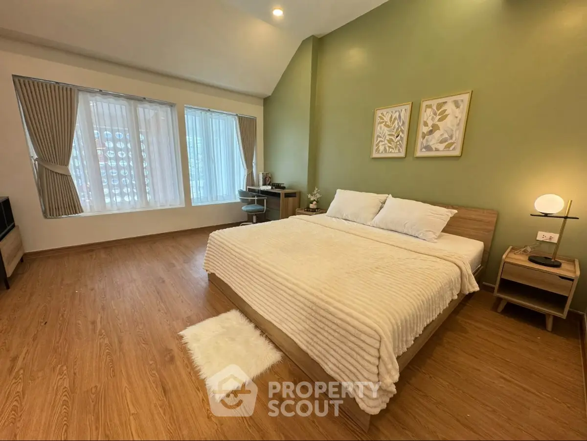Spacious bedroom with modern decor and large windows for natural light.