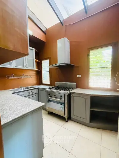 Charming kitchen with gas stove and ample counter space, featuring natural light and modern cabinetry.