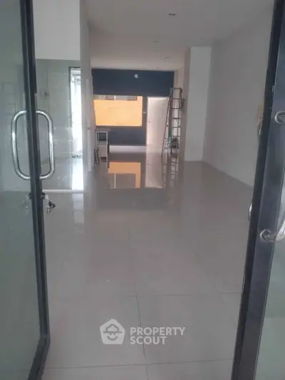 Spacious open-plan interior with glossy tiled floors and modern glass doors, ideal for versatile living or office space.