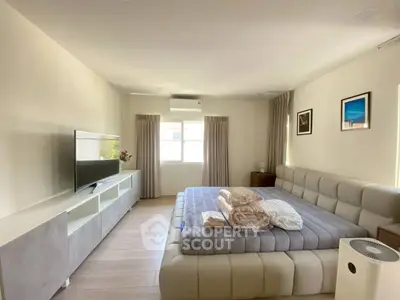 Spacious bedroom with modern decor and large bed, featuring natural light and stylish furnishings.