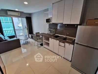 Modern open-layout kitchen with sleek cabinets and cozy living area in a stylish apartment.