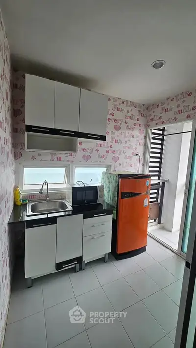 Charming compact kitchen with modern appliances and balcony access, perfect for urban living.