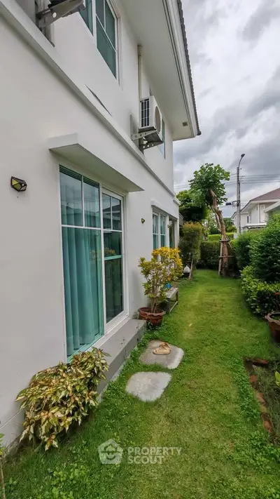 Charming two-story home with lush garden and large windows, perfect for natural light lovers.