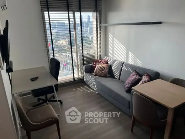 Modern living room with city view, featuring cozy sofa and workspace.