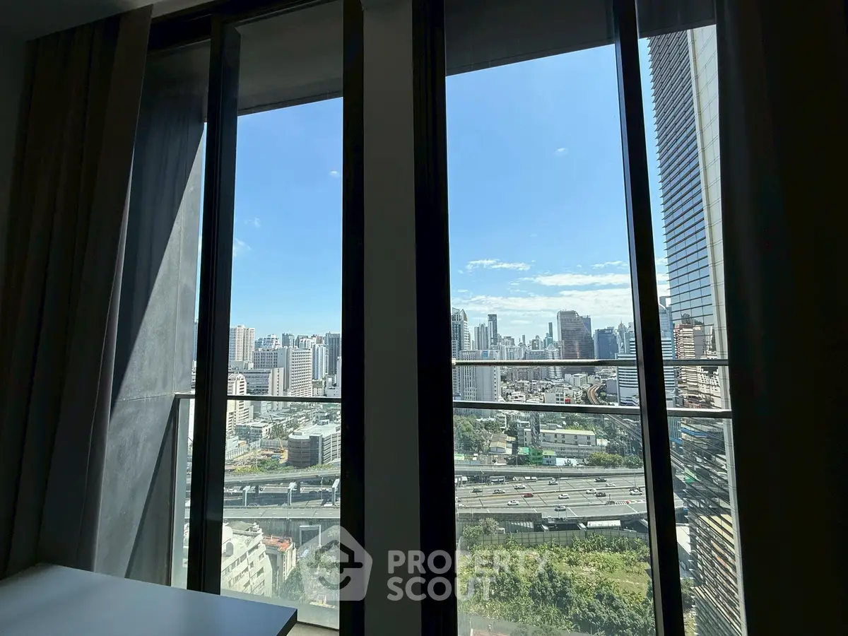 Stunning cityscape view from high-rise apartment window, showcasing urban skyline and blue sky.