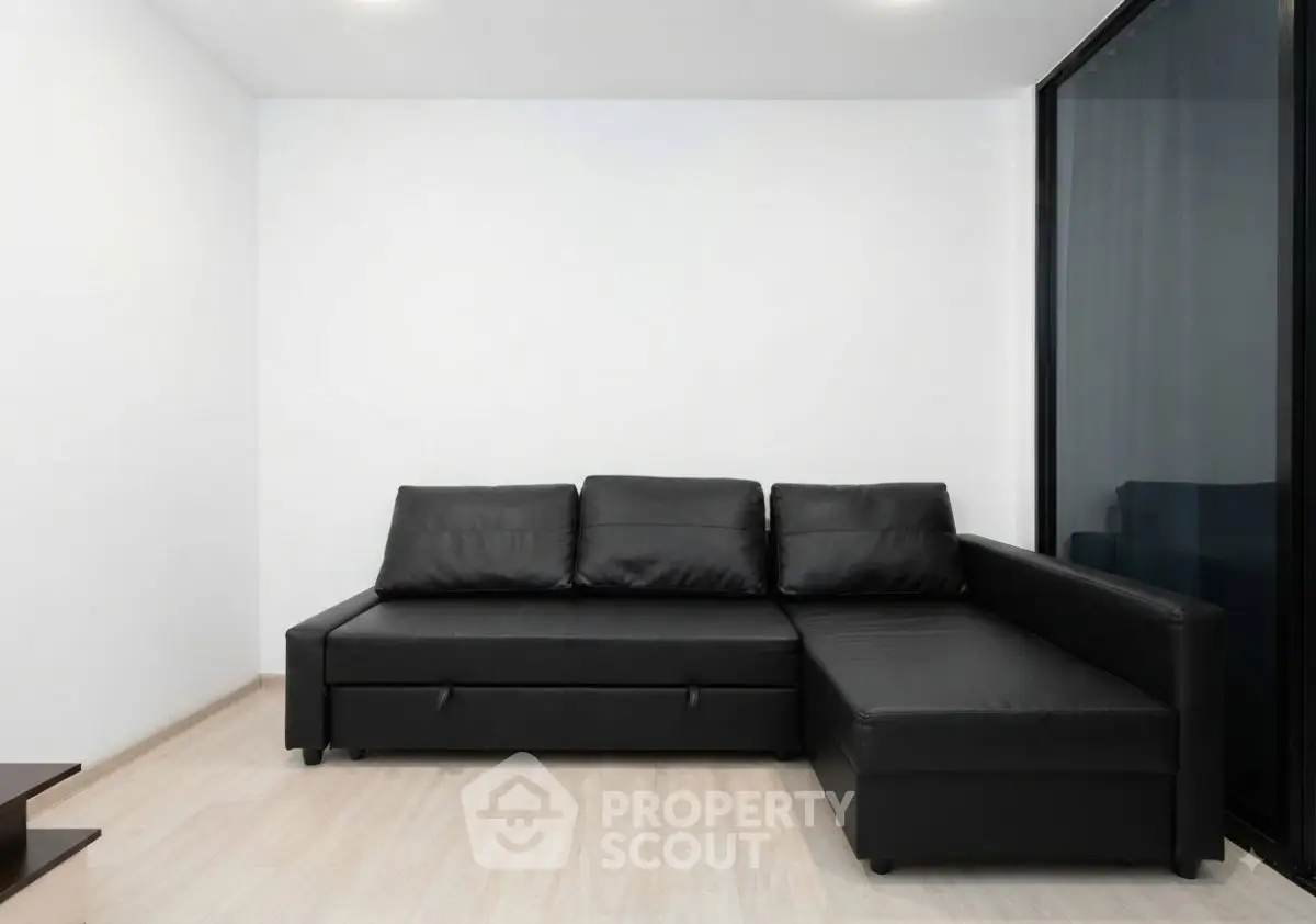 Modern living room with sleek black leather sectional sofa and minimalist design.