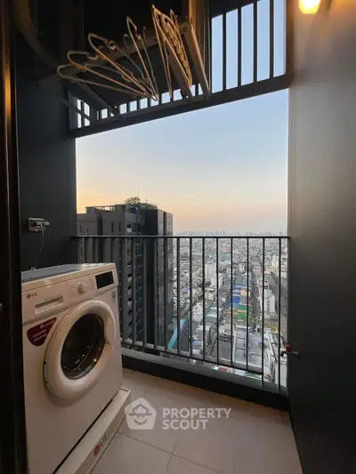 High-rise balcony with washing machine and stunning city view at sunset.