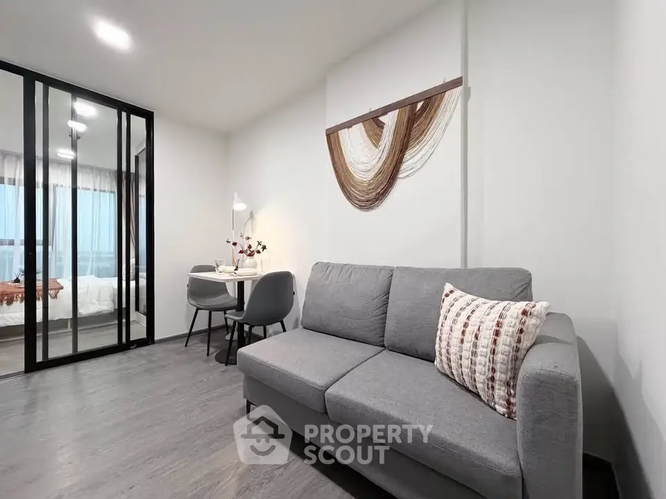 Modern living room with stylish decor and glass partition leading to bedroom