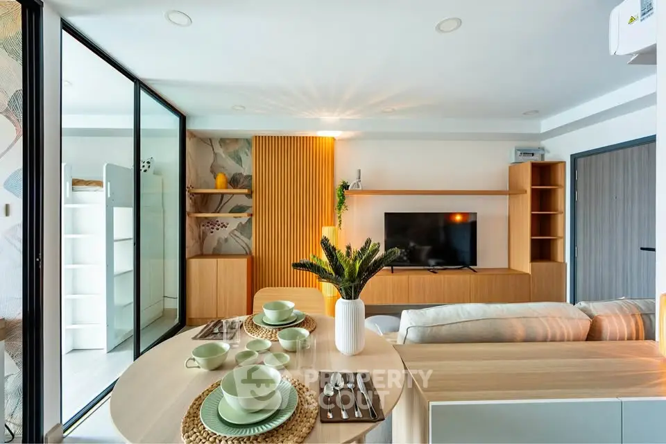 Modern living room with stylish decor and open layout, featuring a dining area and TV setup.
