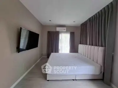 Modern bedroom with large bed and wall-mounted TV, featuring elegant curtains and neutral tones.