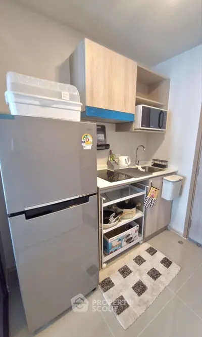 Modern compact kitchen with fridge, microwave, and open shelving