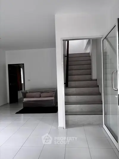Modern interior with sleek staircase and cozy seating area in a minimalist home.