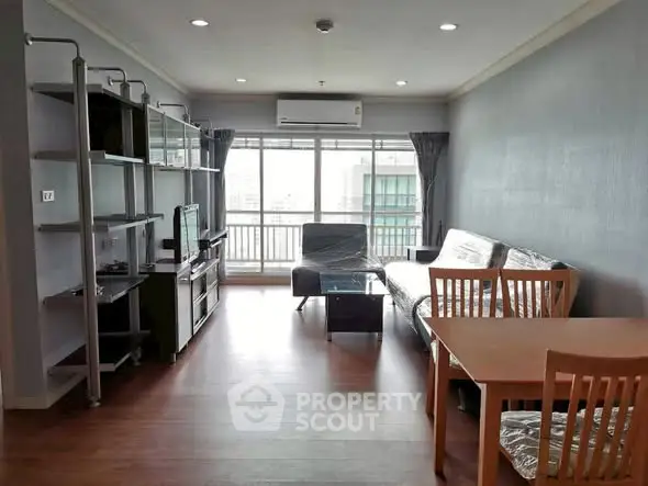Spacious living room with modern furniture and large windows in a high-rise apartment.