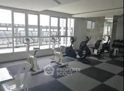 Modern gym with exercise bikes and city view in luxury apartment building.