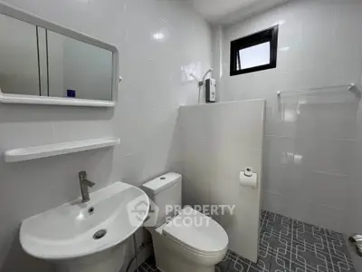 Modern bathroom with sleek white fixtures and stylish tile flooring, featuring a compact design and natural light.