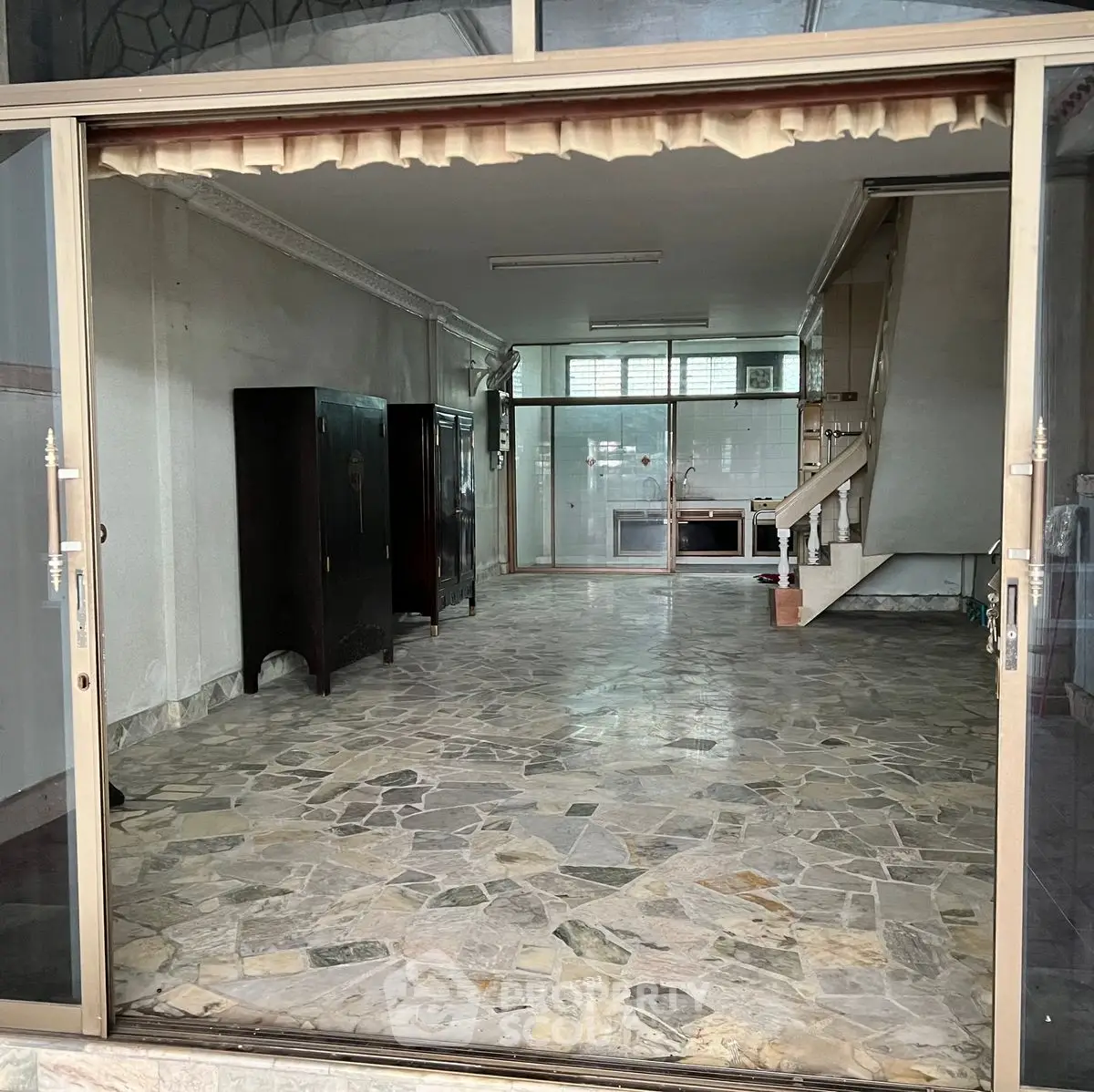 Spacious interior with stone flooring and staircase, ideal for versatile living space.