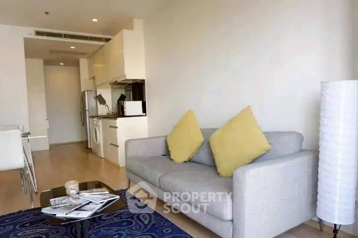 Modern living room with cozy sofa, open kitchen, and stylish decor in a bright apartment.