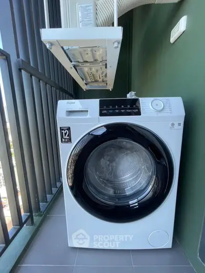 Modern washing machine on a balcony with sleek design and city view.