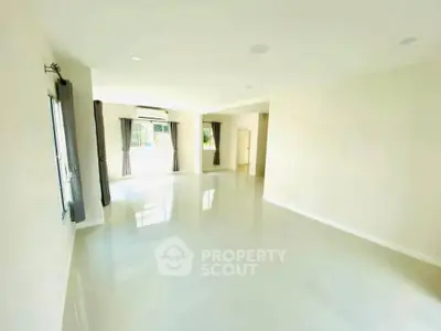 Spacious and bright living room with large windows and glossy floors in modern home.
