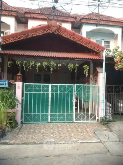 Charming townhouse with gated entrance and decorative plants in a cozy neighborhood.