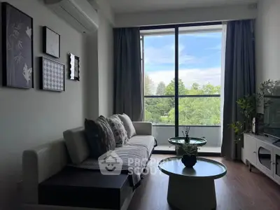 Modern living room with large window and stylish decor overlooking greenery.