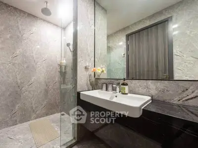 Luxurious marble bathroom with modern fixtures and glass shower enclosure.