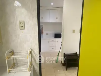 Cozy kitchen with white cabinets and tiled walls, featuring a microwave and storage racks.
