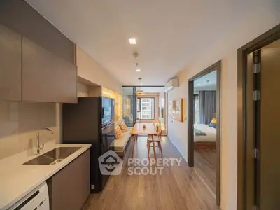 Modern apartment interior with open kitchen and cozy living area, featuring stylish decor and natural light.