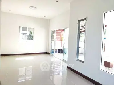 Spacious and bright living room with large windows and glossy tiled floor.