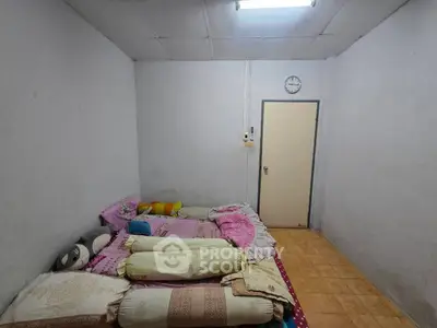 Cozy minimalist bedroom with simple decor and tiled flooring, perfect for a peaceful retreat.