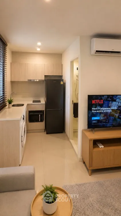 Modern compact living room with open kitchen, featuring sleek appliances and cozy decor.