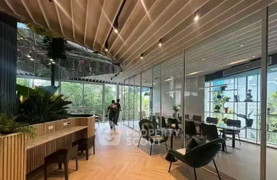 Modern office space with stylish decor and large windows offering natural light and greenery views.