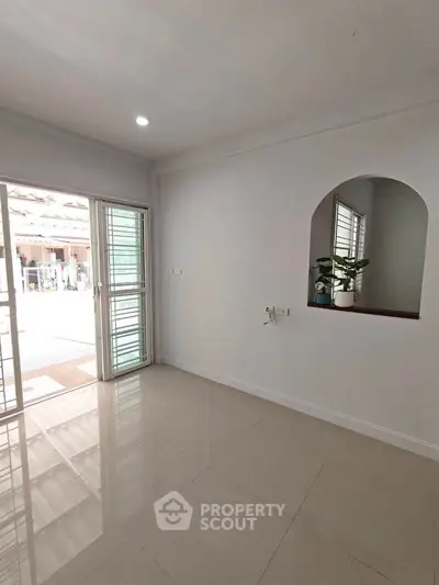 Bright and airy room with large windows and glossy tiled floor, perfect for modern living.