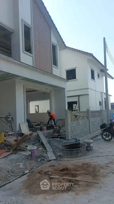 Under-construction modern two-story house with workers and building materials