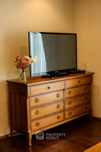 Elegant living room with vintage wooden dresser and modern flat-screen TV, perfect blend of classic and contemporary.